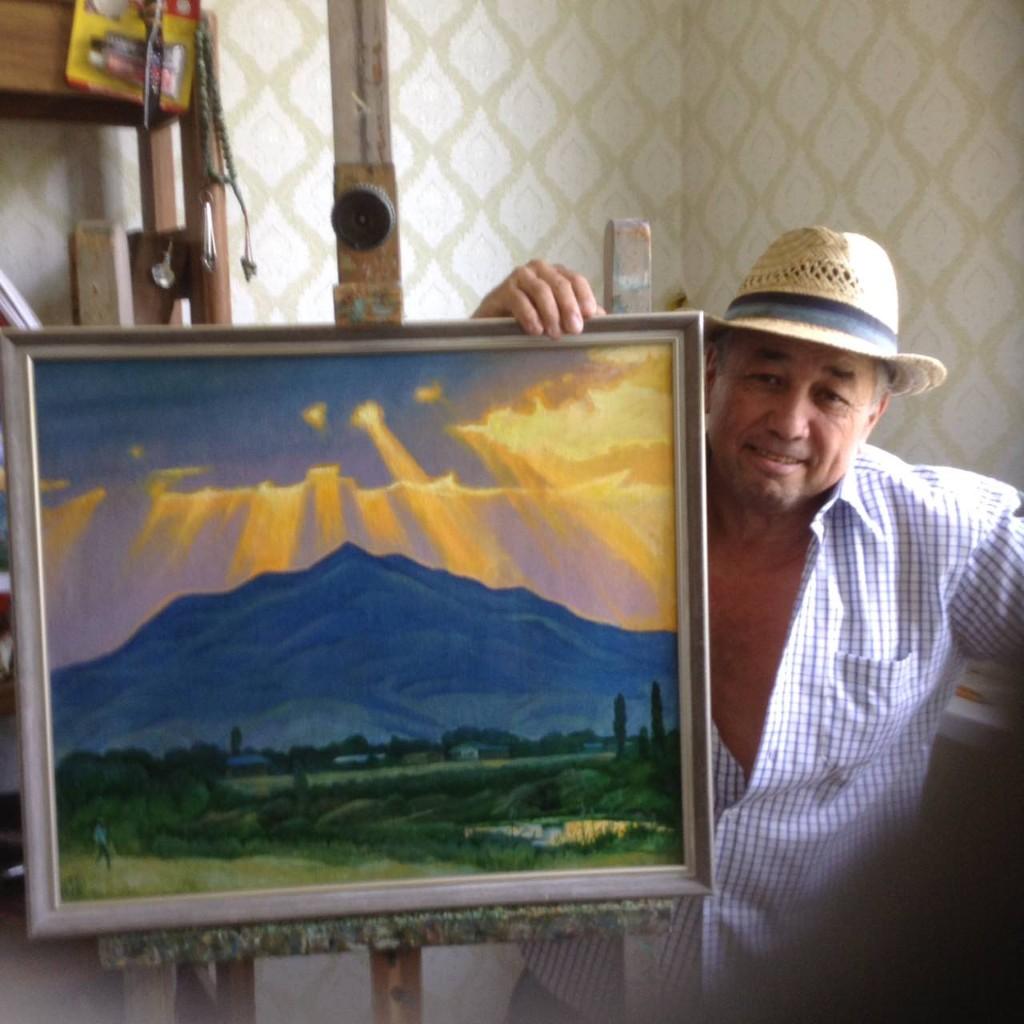 Amon Akilbaev holding one of his paintings